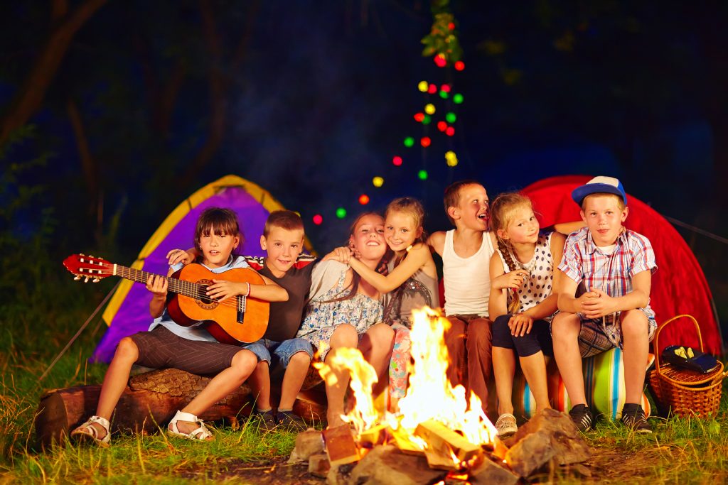 happy kids singing songs around camp fire